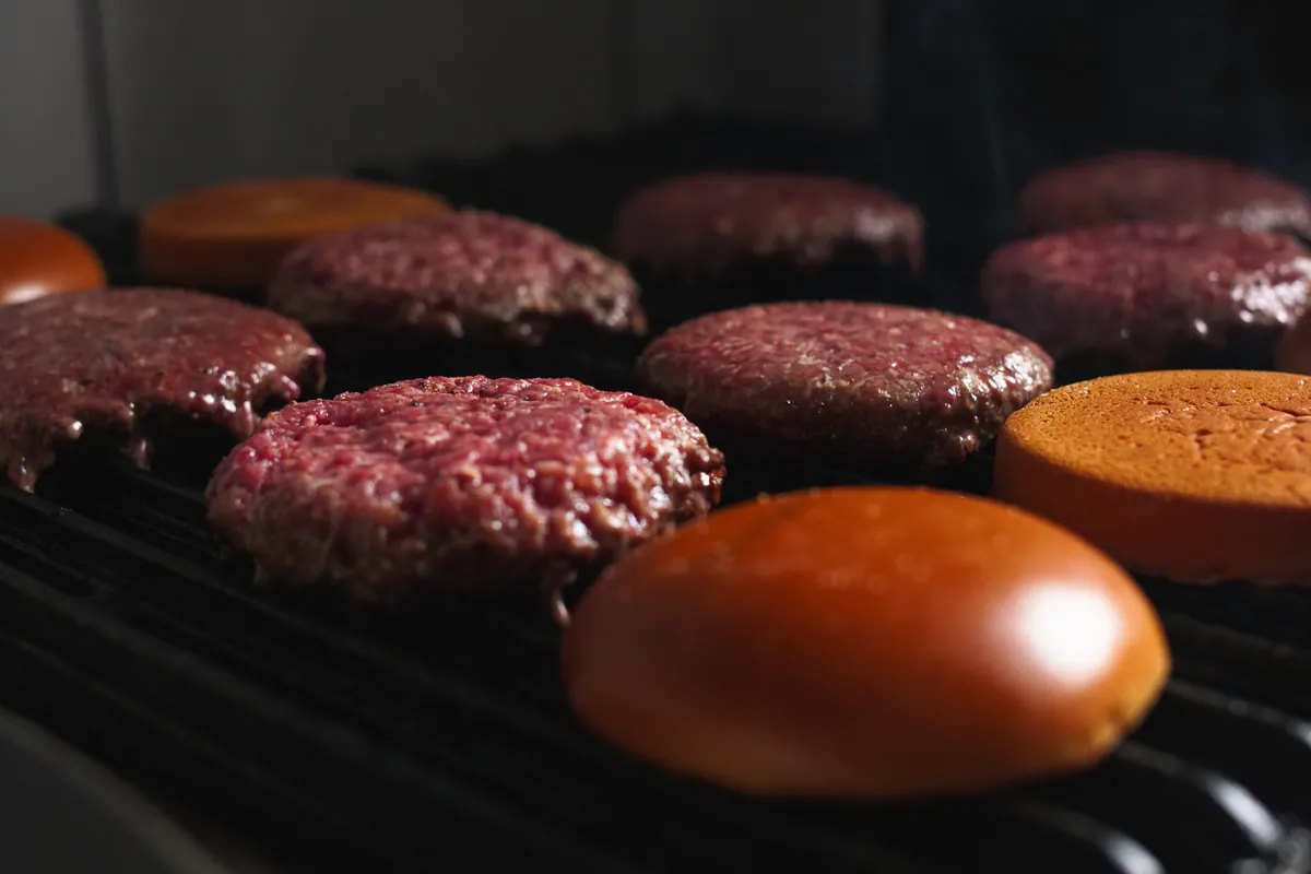 Hambúrgueres e pães na chapa quente da cozinha