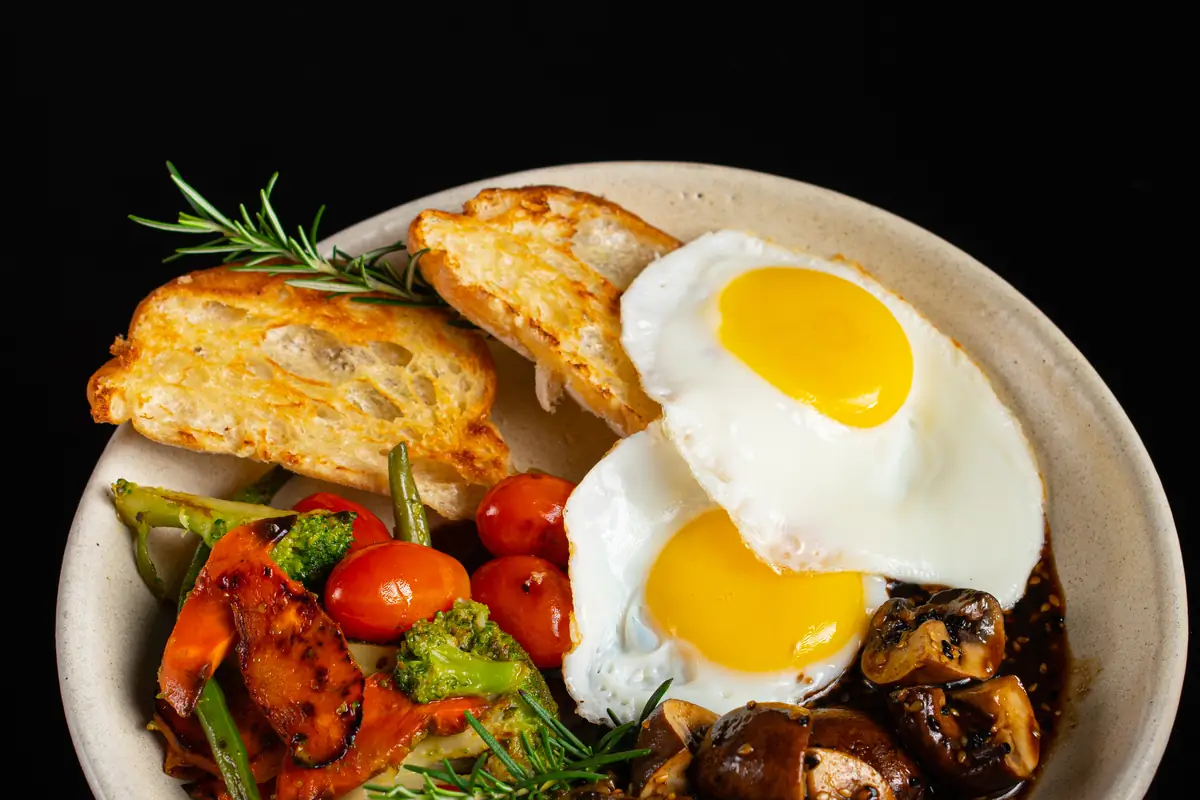 Brunch com ovo, cogumelos e torrada servido em tigela escura